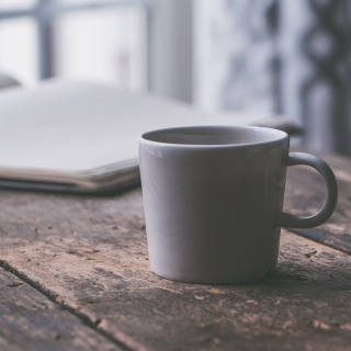 A cup of coffee on a table with a book in the background