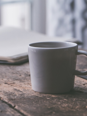 cup of coffee on a table with an open book in the background